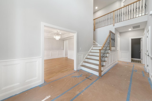 stairs with crown molding and an inviting chandelier