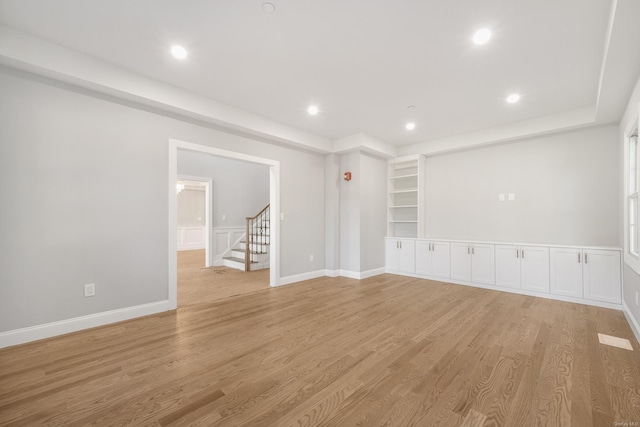 unfurnished room featuring built in shelves and light wood-type flooring