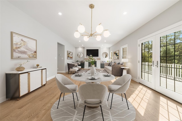 dining area featuring an inviting chandelier, light hardwood / wood-style flooring, and french doors