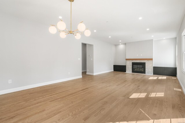 unfurnished living room featuring a notable chandelier and light hardwood / wood-style flooring