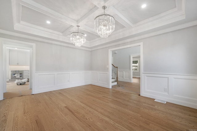 unfurnished dining area with coffered ceiling, a notable chandelier, beam ceiling, and wood-type flooring