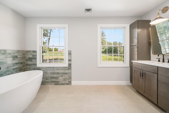 bathroom with vanity, a bathtub, tile patterned floors, and tile walls