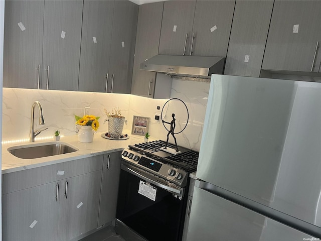 kitchen featuring light stone counters, gray cabinetry, gas range, sink, and white refrigerator