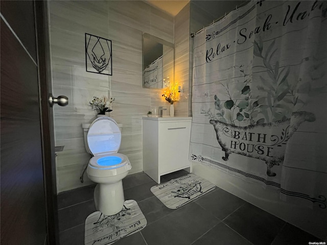 bathroom featuring tile patterned floors, vanity, toilet, and tile walls