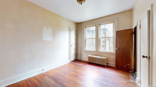 unfurnished room featuring wood-type flooring and radiator heating unit