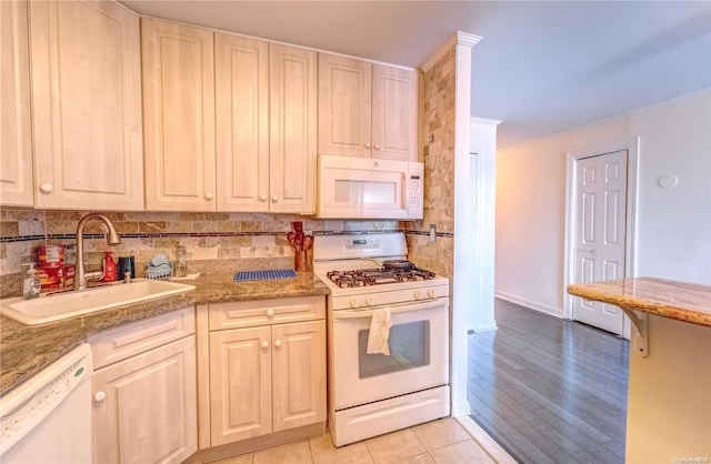 kitchen with white appliances, light hardwood / wood-style floors, backsplash, and sink