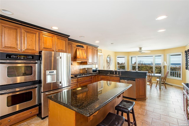 kitchen featuring kitchen peninsula, appliances with stainless steel finishes, a center island, and backsplash