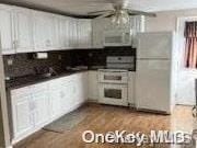 kitchen with white cabinets, ceiling fan, and light hardwood / wood-style flooring