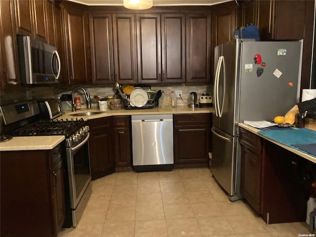 kitchen featuring backsplash, sink, light tile patterned floors, dark brown cabinets, and stainless steel appliances