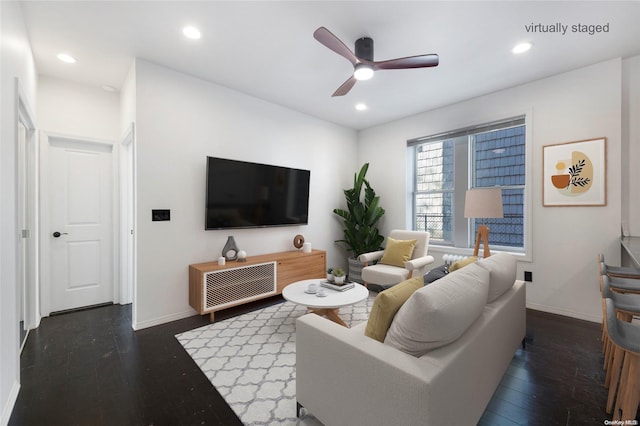 living room featuring ceiling fan and dark wood-type flooring