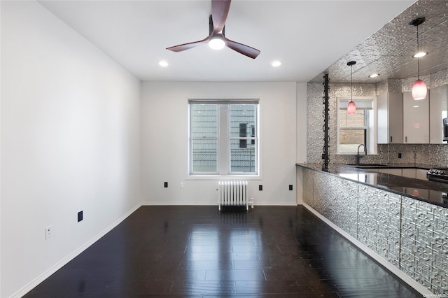 interior space featuring dark hardwood / wood-style floors, ceiling fan, radiator heating unit, and sink