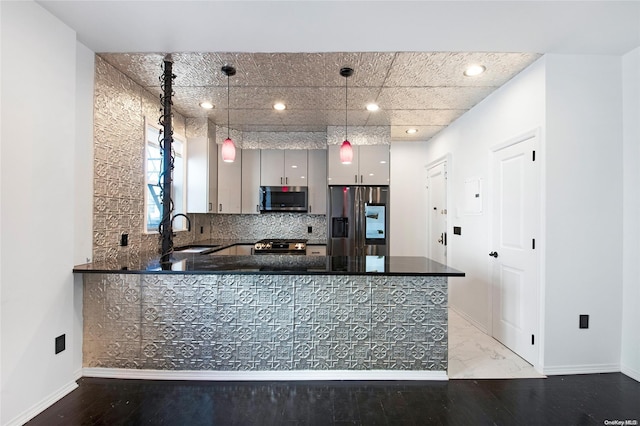 kitchen with pendant lighting, sink, kitchen peninsula, and stainless steel appliances