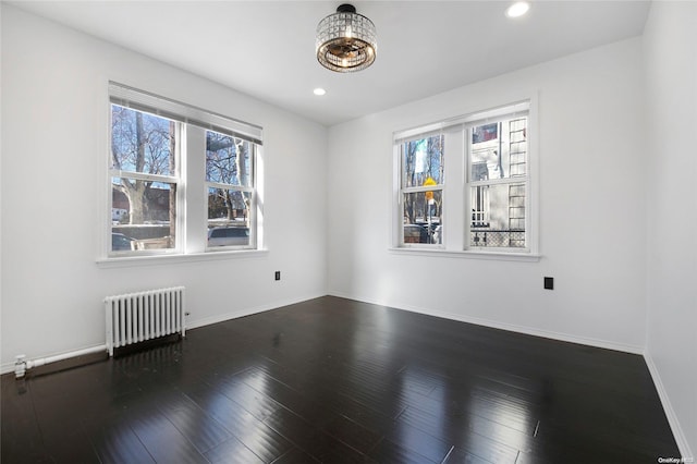 spare room featuring dark hardwood / wood-style flooring and radiator