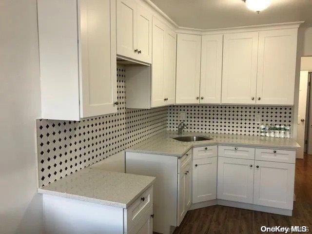 kitchen with white cabinetry, sink, dark wood-type flooring, and light stone counters