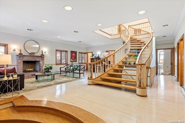 stairway with a high end fireplace, hardwood / wood-style floors, plenty of natural light, and ornamental molding