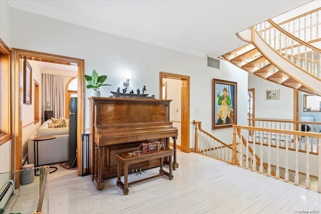 miscellaneous room featuring ornamental molding, a baseboard radiator, and light wood-type flooring