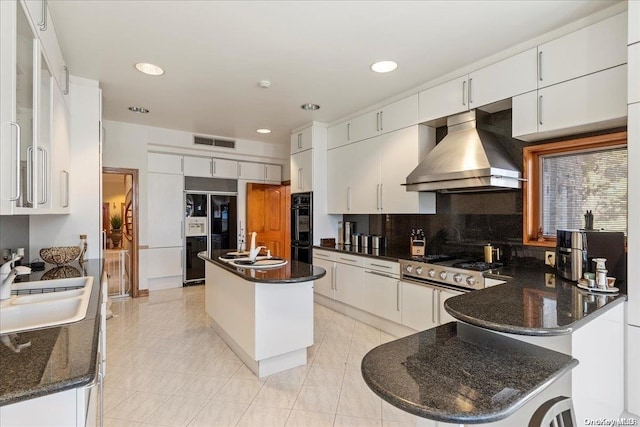 kitchen with a center island, white cabinetry, and wall chimney range hood