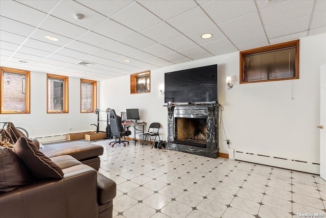 living room featuring a baseboard radiator, a drop ceiling, and a premium fireplace