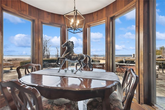 dining room with plenty of natural light, wood walls, and a chandelier