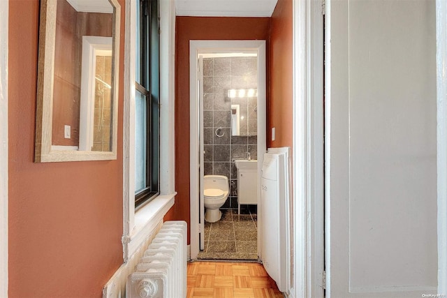 hall featuring sink, light parquet flooring, radiator, and tile walls