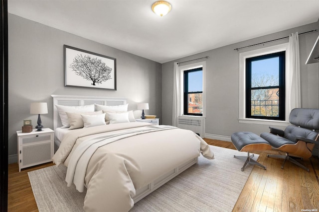 bedroom featuring radiator heating unit and hardwood / wood-style flooring