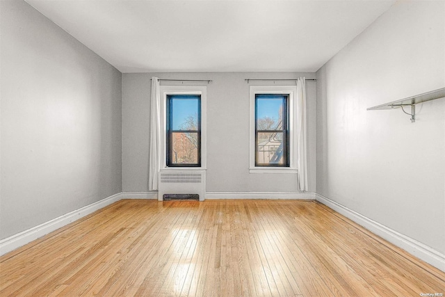 spare room with radiator heating unit and light wood-type flooring