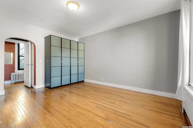 unfurnished bedroom with radiator heating unit and light hardwood / wood-style flooring