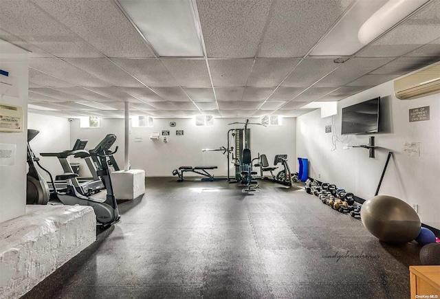 exercise area with a wall unit AC and a drop ceiling