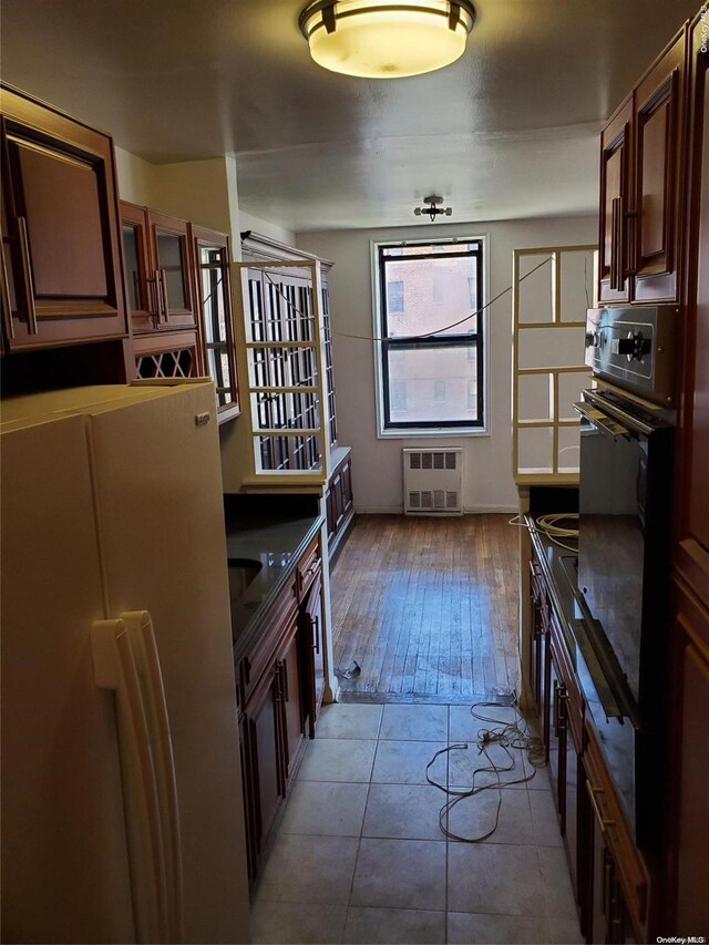 kitchen featuring black oven, white refrigerator, and light wood-type flooring