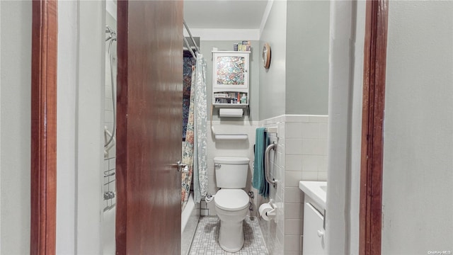 bathroom with toilet, vanity, tile patterned floors, and tile walls