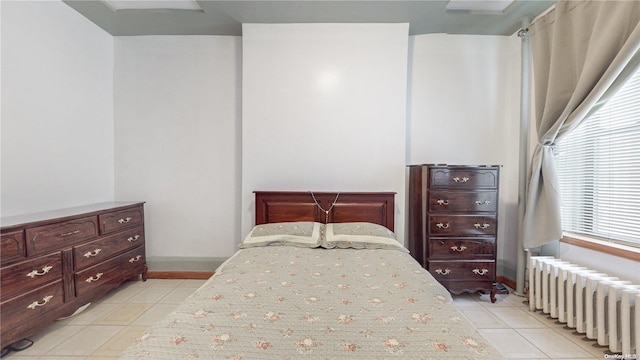 bedroom with radiator heating unit and light tile patterned floors