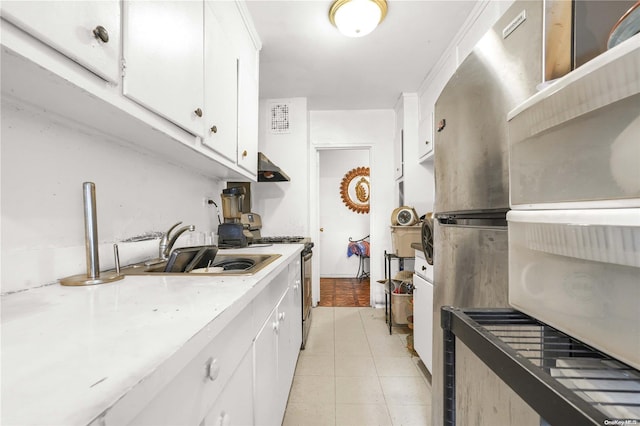 kitchen with white stove, white cabinets, sink, light tile patterned floors, and extractor fan