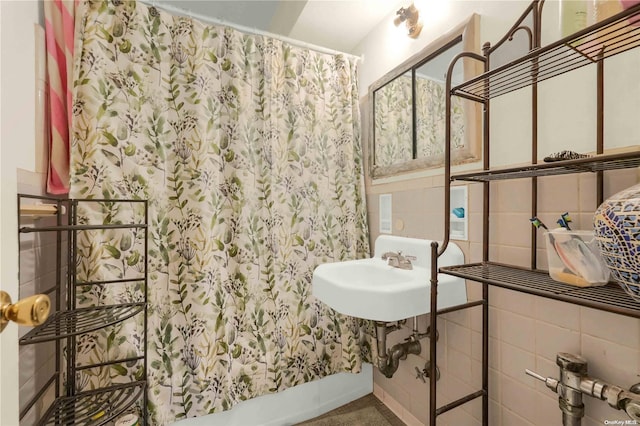 bathroom with curtained shower, sink, and tile walls