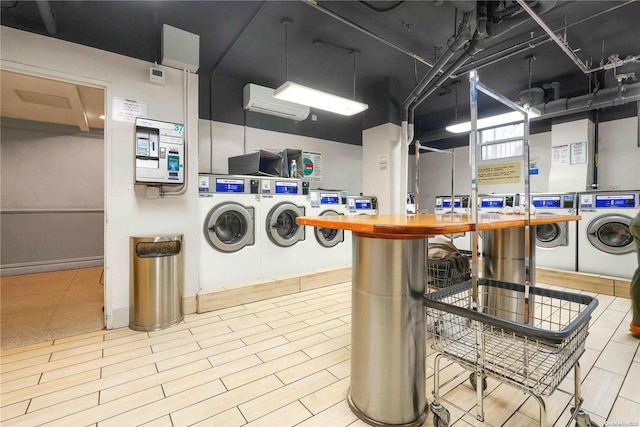 laundry area featuring a wall unit AC, hardwood / wood-style floors, and independent washer and dryer