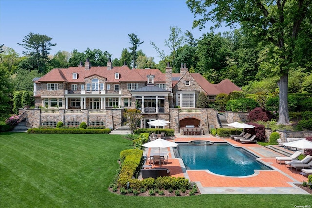 rear view of property with a yard, a patio area, and an outdoor fireplace