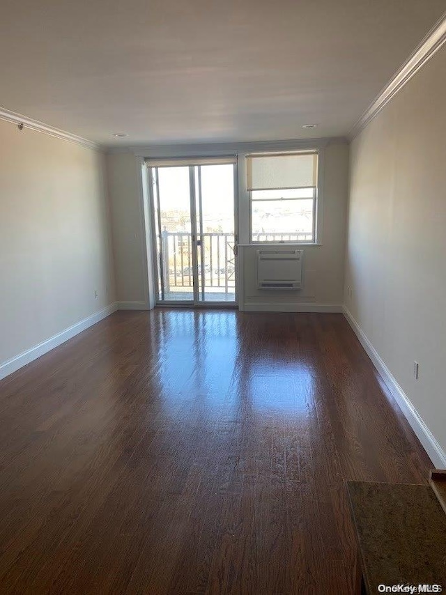 spare room featuring dark hardwood / wood-style flooring, ornamental molding, and a wall mounted AC