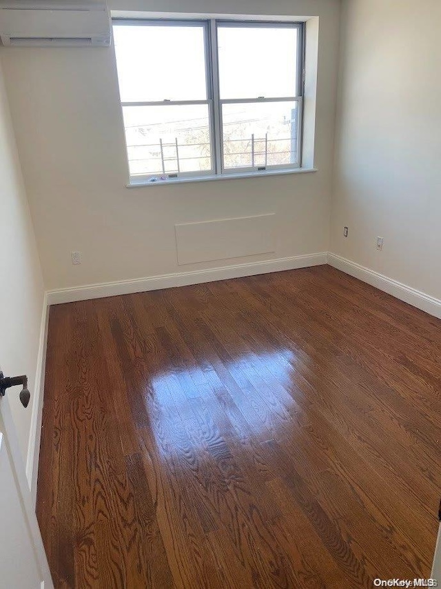 unfurnished room with dark hardwood / wood-style floors, a healthy amount of sunlight, and an AC wall unit