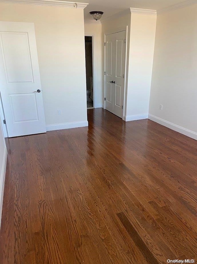 empty room with dark wood-type flooring and ornamental molding