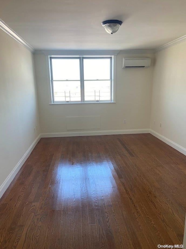 empty room featuring an AC wall unit, crown molding, and dark hardwood / wood-style flooring