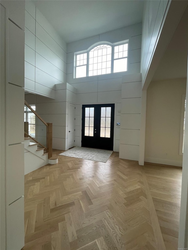 foyer featuring baseboards, stairs, a high ceiling, and french doors