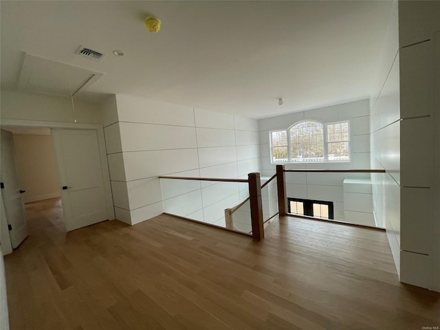 empty room featuring attic access, visible vents, and wood finished floors