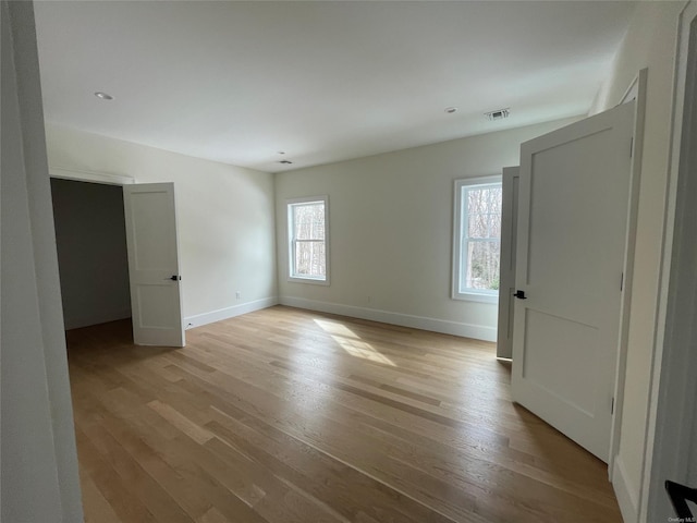 unfurnished room featuring baseboards, visible vents, and light wood-style floors