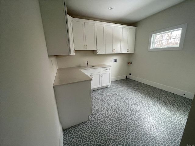 laundry area featuring cabinet space, baseboards, light floors, washer hookup, and a sink