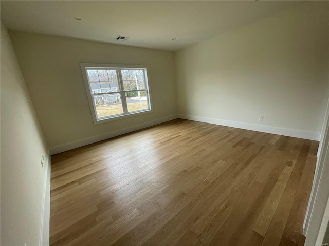 unfurnished room with light wood finished floors, visible vents, and baseboards