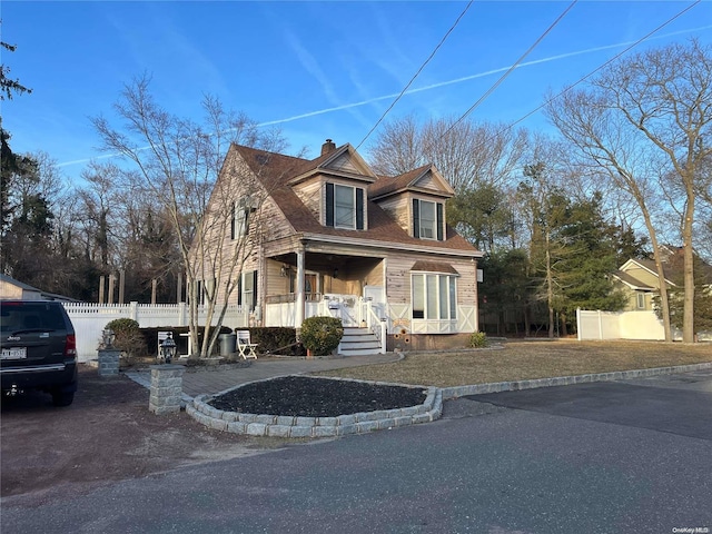 cape cod house featuring covered porch