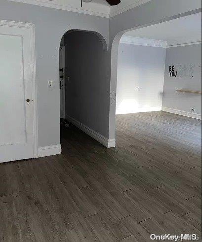 empty room with dark hardwood / wood-style floors, ceiling fan, and ornamental molding