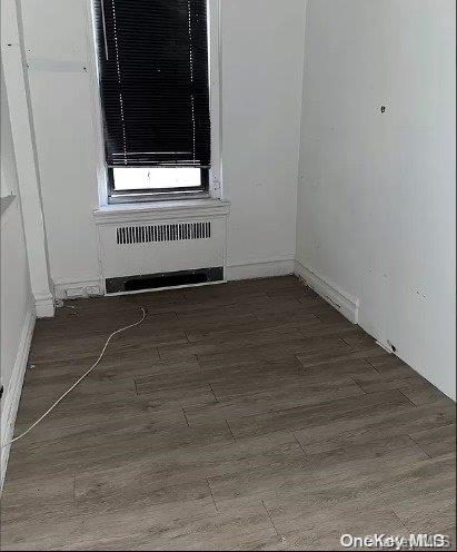 unfurnished room with dark hardwood / wood-style floors and radiator