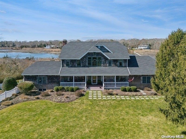 view of front of property with a porch, a water view, and a front lawn