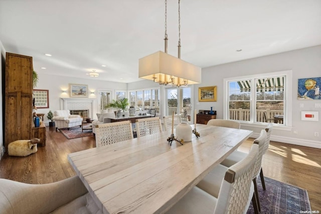 dining space with hardwood / wood-style flooring, an inviting chandelier, and a brick fireplace