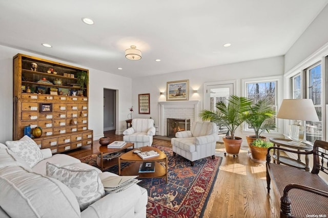 living room featuring wood-type flooring and a brick fireplace